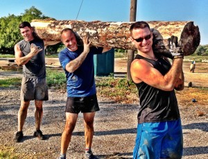 Jesse James Retherford, Monte, and Jonah carrying a giant log. The Art of Fitness Austin Texas.